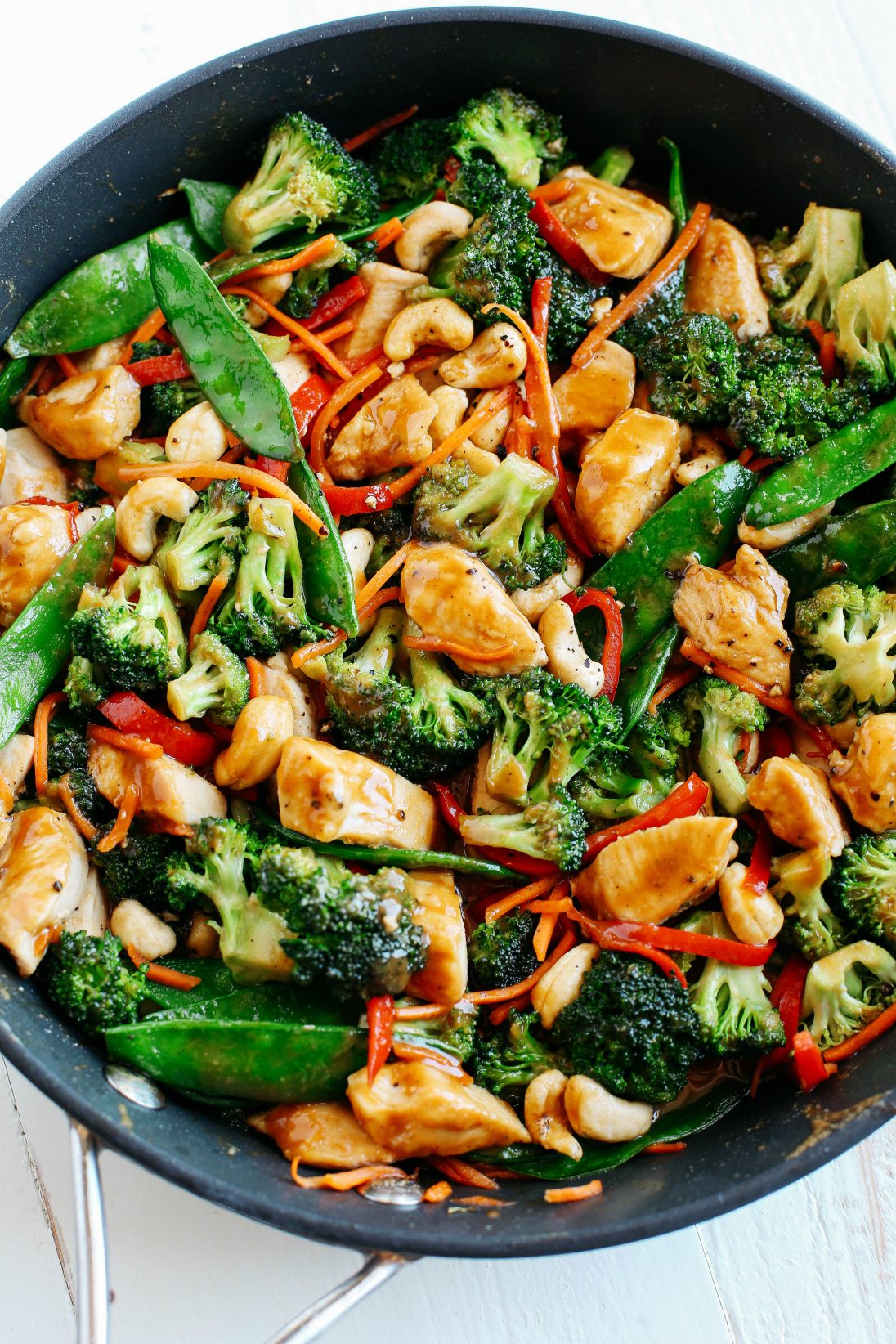 A plate of Cashew Chicken Stir Fry over cauliflower rice with a variety of vegetables including broccoli, carrots, and bell peppers, garnished with cashews.